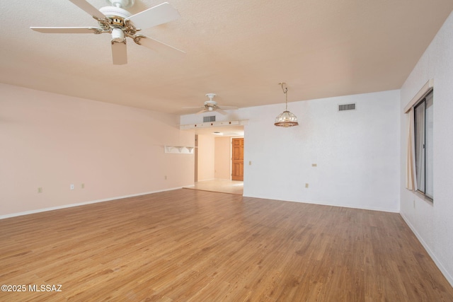 spare room with light wood-style floors, visible vents, ceiling fan, and baseboards