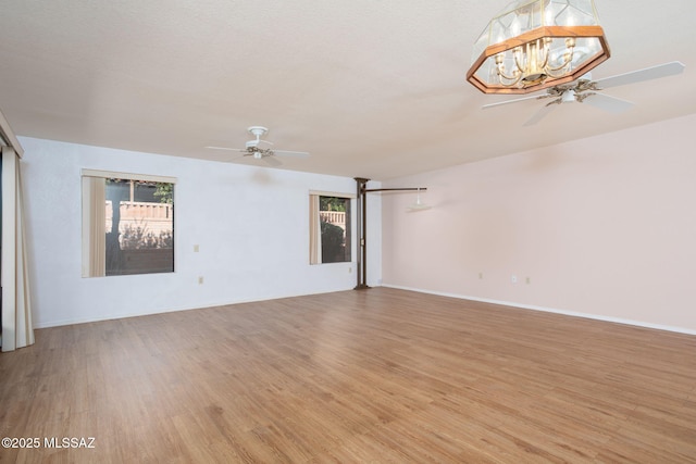 interior space featuring light wood-style flooring, baseboards, and ceiling fan with notable chandelier