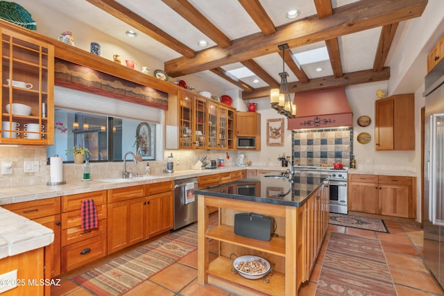 kitchen featuring appliances with stainless steel finishes, pendant lighting, sink, backsplash, and a center island with sink