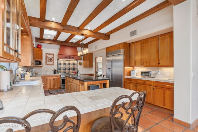 kitchen with pendant lighting, built in appliances, tasteful backsplash, custom range hood, and kitchen peninsula