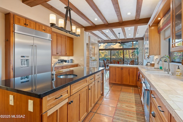 kitchen featuring pendant lighting, appliances with stainless steel finishes, a kitchen island with sink, and sink