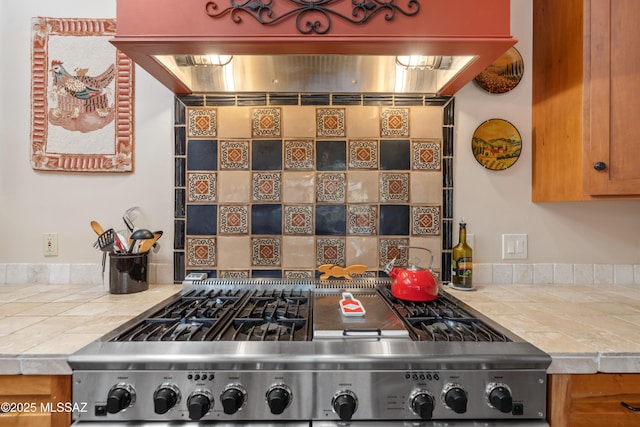 kitchen featuring range, tile countertops, and exhaust hood