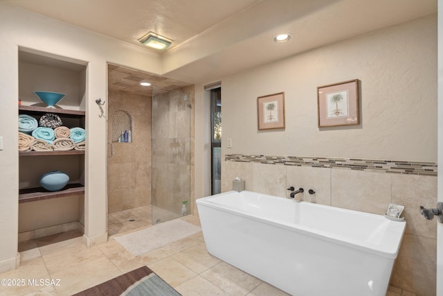 bathroom with tile patterned flooring, shower with separate bathtub, and tile walls