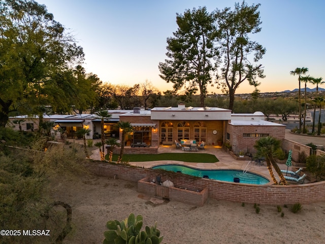 back house at dusk with a patio area