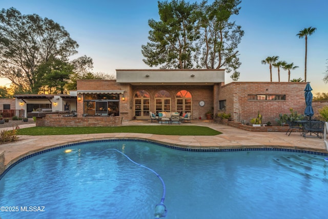 pool at dusk featuring a patio