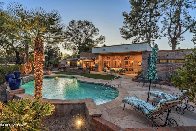 pool at dusk with a patio area