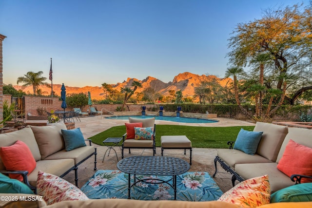 patio terrace at dusk with an outdoor hangout area, a fenced in pool, and a mountain view