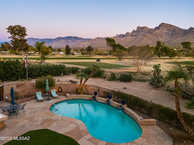 pool at dusk with a mountain view and a patio