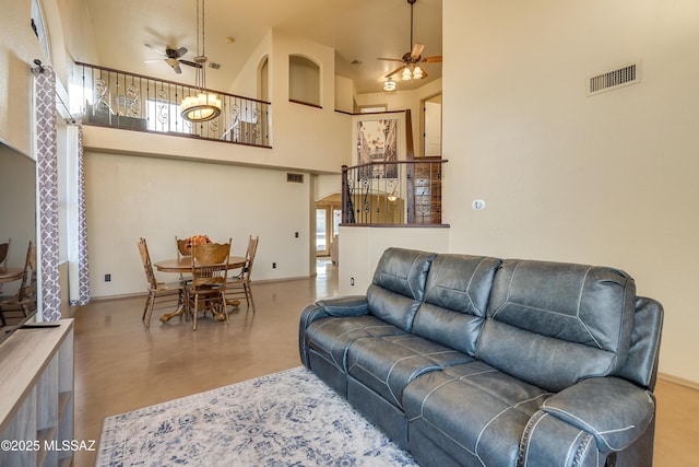 living room featuring a towering ceiling, concrete floors, and ceiling fan