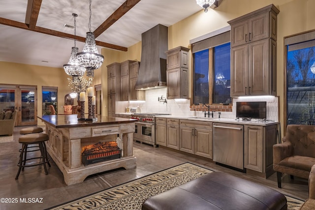 kitchen with tasteful backsplash, wall chimney exhaust hood, appliances with stainless steel finishes, a center island, and a sink