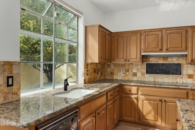 kitchen featuring sink, black appliances, stone countertops, and backsplash