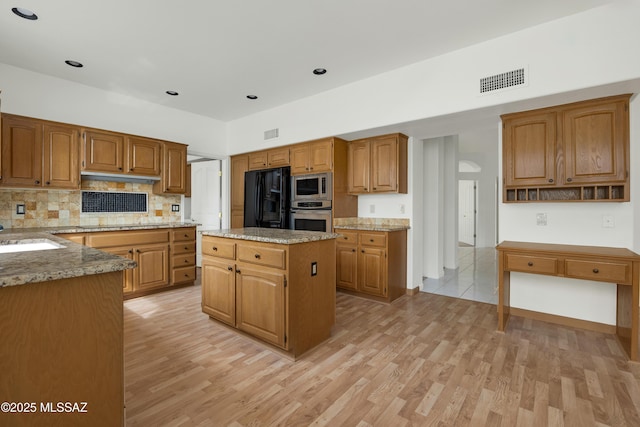 kitchen with appliances with stainless steel finishes, sink, a kitchen island, and light hardwood / wood-style flooring