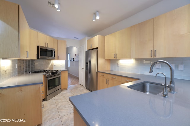 kitchen featuring light brown cabinets, visible vents, arched walkways, a sink, and stainless steel appliances