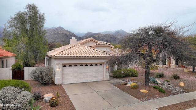 mediterranean / spanish-style house with driveway, a chimney, stucco siding, a tile roof, and a mountain view