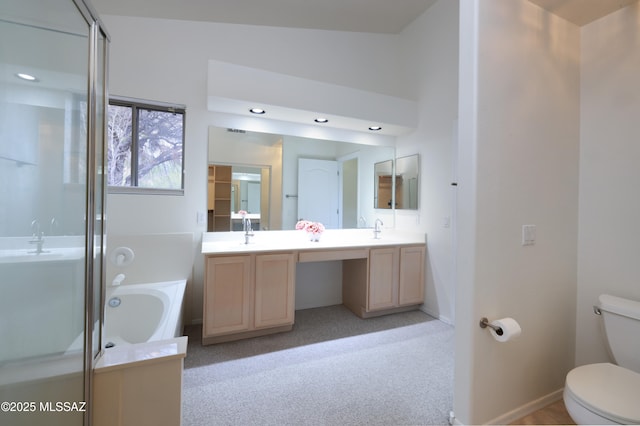 bathroom featuring a sink, a garden tub, toilet, and vaulted ceiling