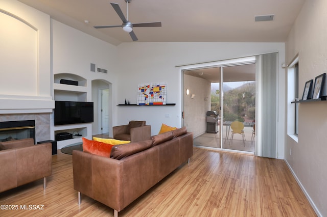 living area featuring arched walkways, light wood-type flooring, a ceiling fan, and vaulted ceiling