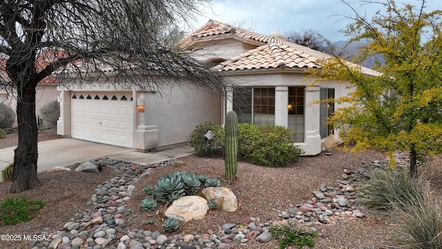 view of front facade featuring stucco siding, an attached garage, a tile roof, and driveway