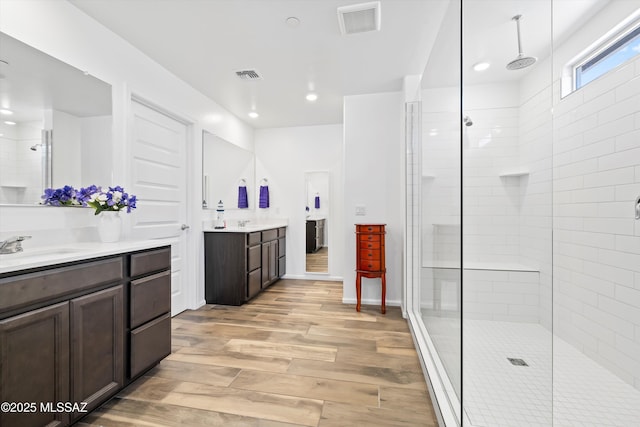 full bathroom featuring a sink, two vanities, wood finished floors, and visible vents
