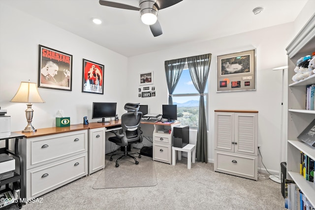 office space with a ceiling fan, light colored carpet, and baseboards