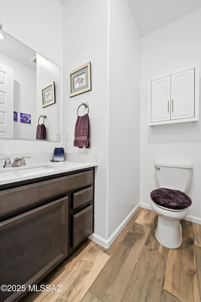bathroom featuring toilet, wood finished floors, vanity, and baseboards