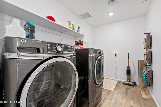 washroom with laundry area, visible vents, and washing machine and clothes dryer