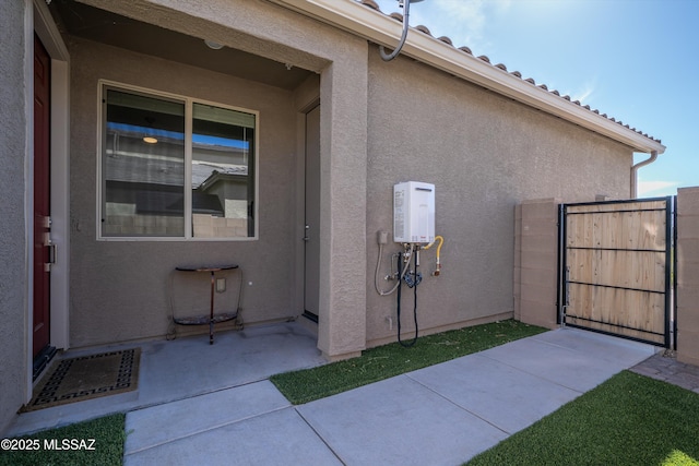 exterior space with a gate, a patio, and stucco siding