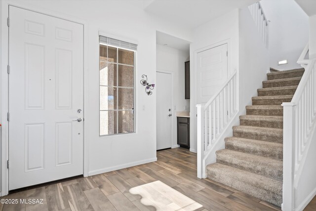 entryway featuring light wood finished floors, stairway, and baseboards