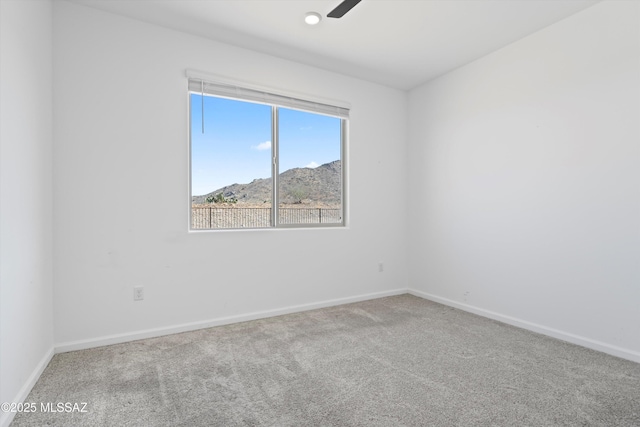 spare room featuring carpet floors, a mountain view, and baseboards