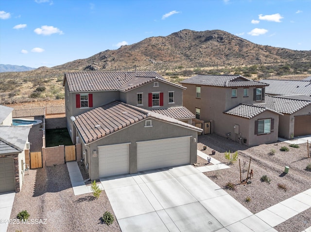 view of front facade with driveway, fence, a mountain view, and stucco siding