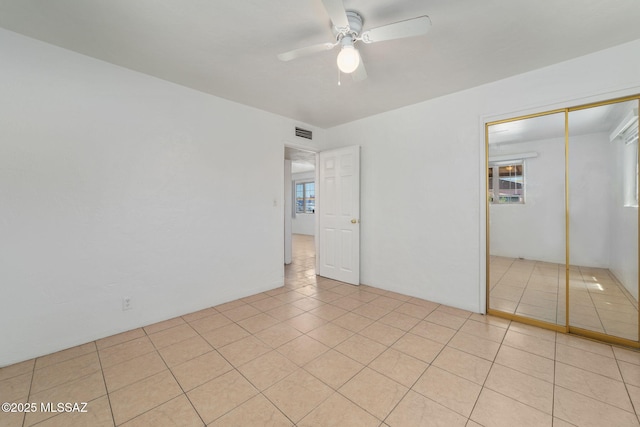 unfurnished bedroom with light tile patterned floors, a closet, and ceiling fan