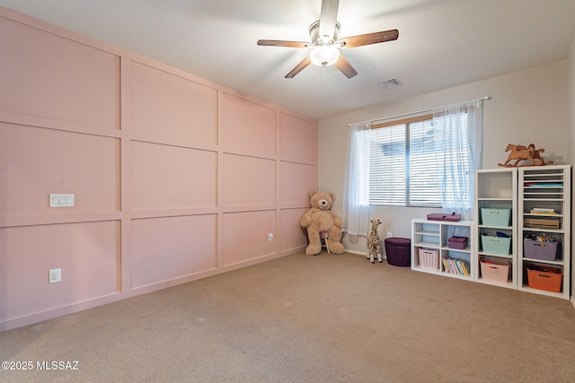 playroom with a decorative wall, carpet, visible vents, and ceiling fan