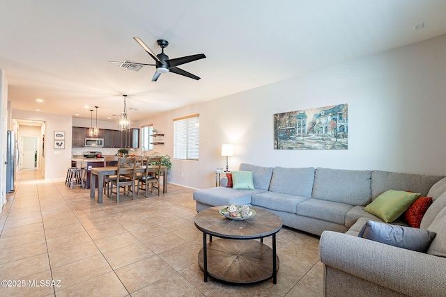 living area with light tile patterned floors, a ceiling fan, visible vents, baseboards, and recessed lighting