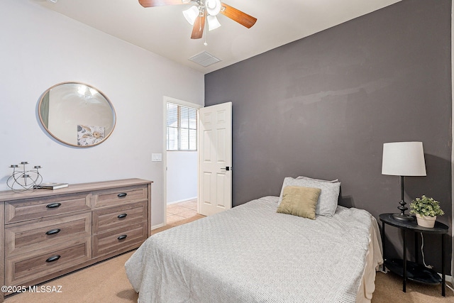 bedroom with baseboards, a ceiling fan, visible vents, and light carpet