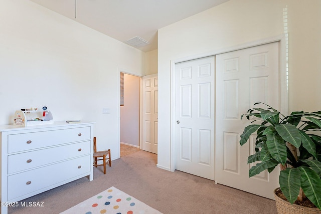 bedroom featuring light colored carpet, visible vents, and a closet