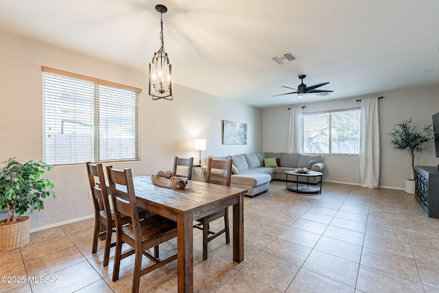 dining space with light tile patterned floors, visible vents, ceiling fan with notable chandelier, and baseboards