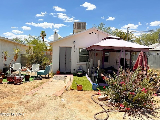 rear view of property with a gazebo and cooling unit