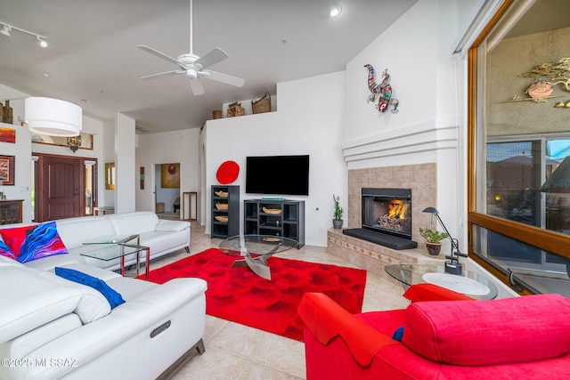 living room featuring ceiling fan, a tiled fireplace, and light tile patterned floors