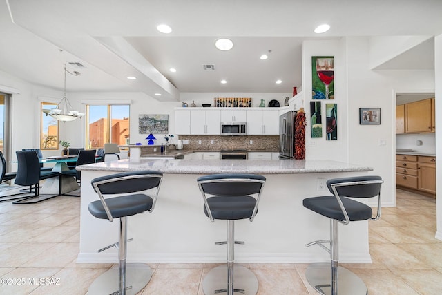 kitchen with tasteful backsplash, light tile patterned floors, pendant lighting, stainless steel appliances, and white cabinets