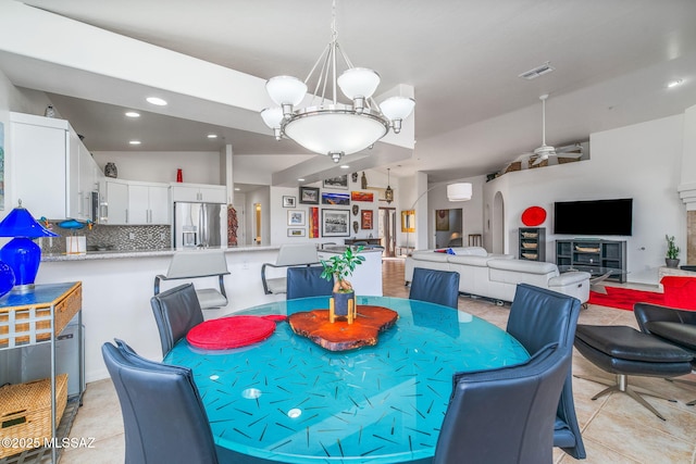 dining area with light tile patterned flooring, a wall mounted AC, and ceiling fan with notable chandelier