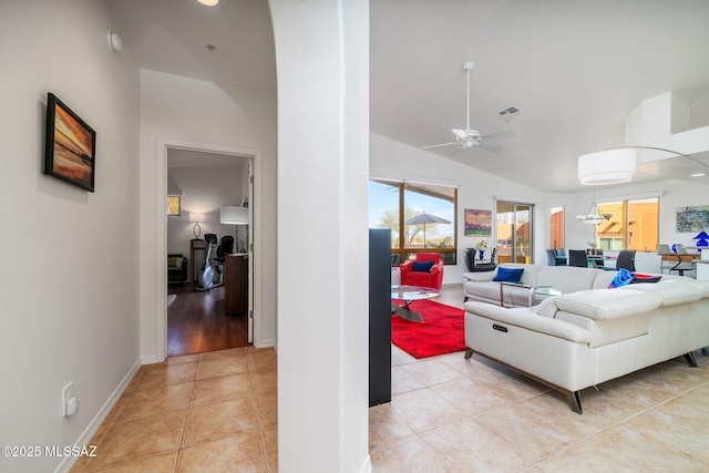 living room with ceiling fan, vaulted ceiling, and light tile patterned floors