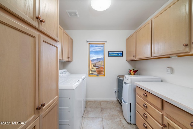 clothes washing area featuring cabinets, separate washer and dryer, and light tile patterned floors