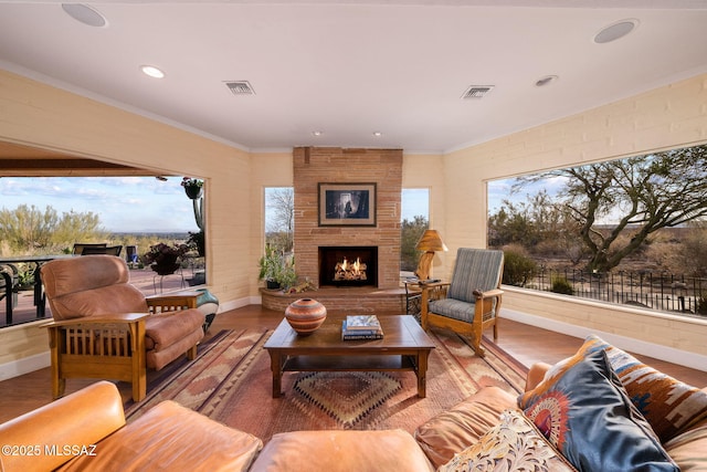 living room featuring ornamental molding, wood-type flooring, and a fireplace