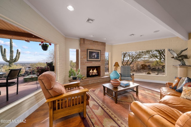 living room with a large fireplace, wood-type flooring, and ornamental molding