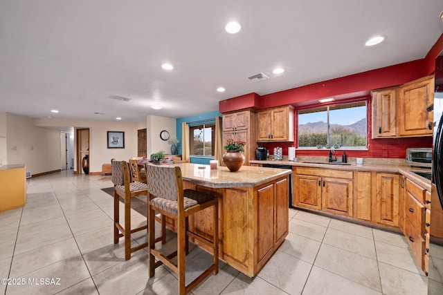 kitchen featuring a mountain view, a center island, light tile patterned floors, and light stone counters