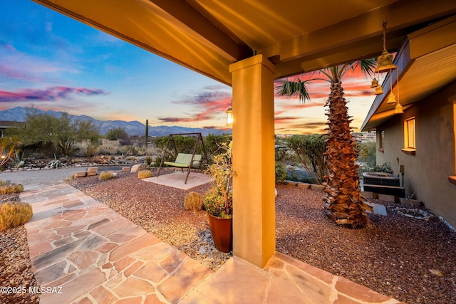 patio terrace at dusk featuring a mountain view