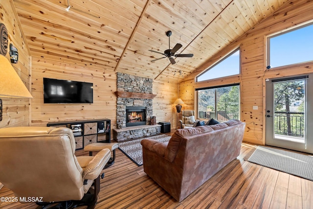 living room featuring wooden ceiling, wood walls, wood-type flooring, and a stone fireplace