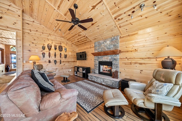 living area with a fireplace, wood ceiling, wooden walls, wood finished floors, and high vaulted ceiling
