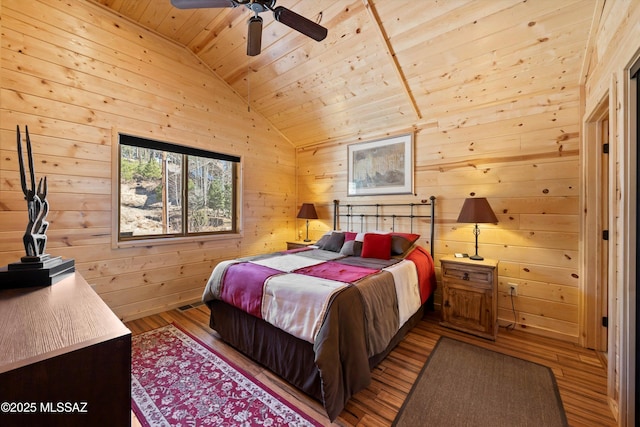 bedroom featuring wooden walls, a ceiling fan, lofted ceiling, wood-type flooring, and wood ceiling