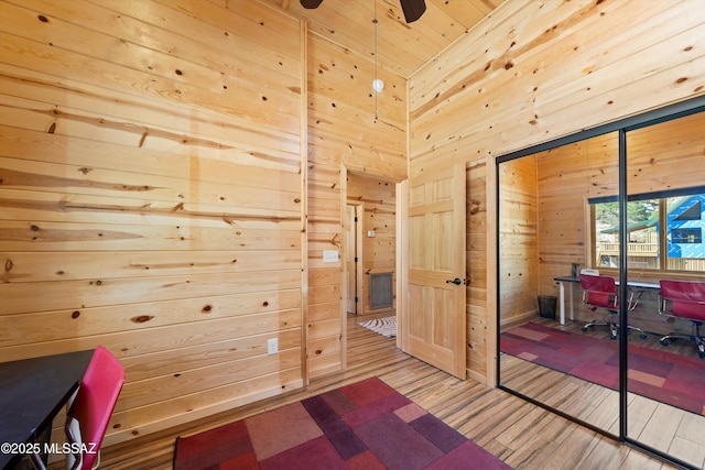 unfurnished office featuring a ceiling fan, wooden ceiling, wooden walls, and wood finished floors