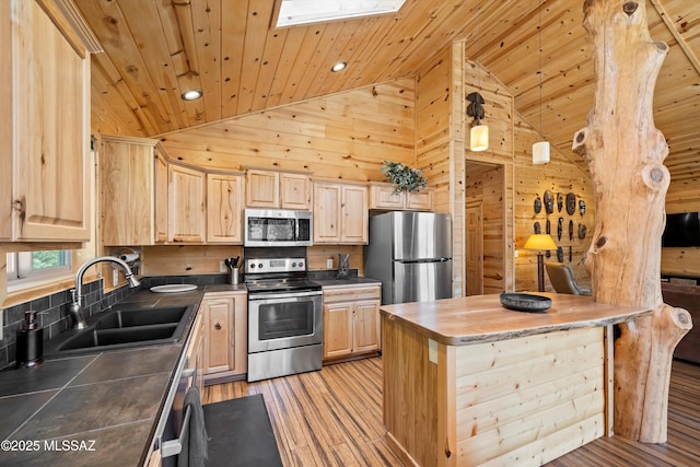 kitchen with a skylight, wood ceiling, stainless steel appliances, light brown cabinetry, and a sink